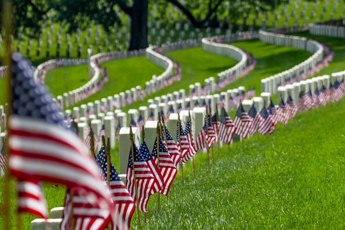 picture of lots of white gravestones with usa flags at arlington cemetery